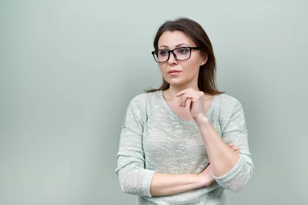 Sérieux femme d'âge moyen avec des lunettes regardant sur le côté, copier l'espace fond vert — Photo