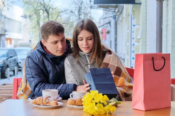 Pareja joven en la cafetería al aire libre con bolsas de compras, beber café — Foto de Stock