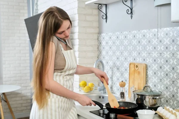 Giovane bella donna che cucina a casa in cucina, fritture uova con salsicce — Foto Stock