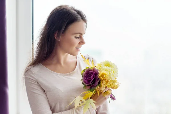 Young woman with bouquet of yellow fallen leaves and autumn flowers — Stock Photo, Image