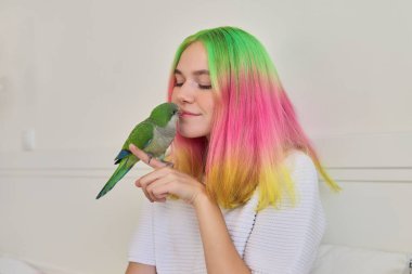 Elinde yeşil papağan olan siyah saçlı genç kız.