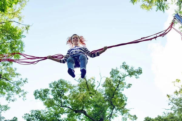 Adolescente menina se divertindo pulando no trampolim com cordas elásticas — Fotografia de Stock