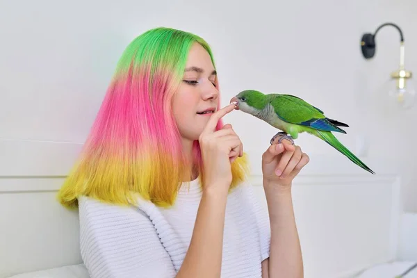Trendy s barvenými vlasy teenager dívka se zeleným papouškem na ruce — Stock fotografie