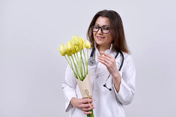 Портрет жінки-лікаря зі стетоскопом, що тримає букет квітів — стокове фото