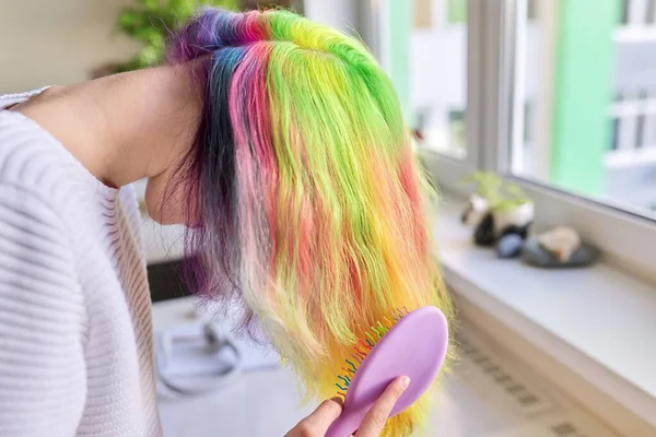 Chica adolescente de moda con el pelo teñido arco iris de moda peinar el pelo en casa — Foto de Stock