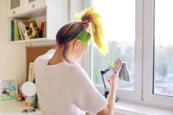 Menina adolescente na moda com cabelo tingido de arco-íris moderno pentear o cabelo em casa — Fotografia de Stock