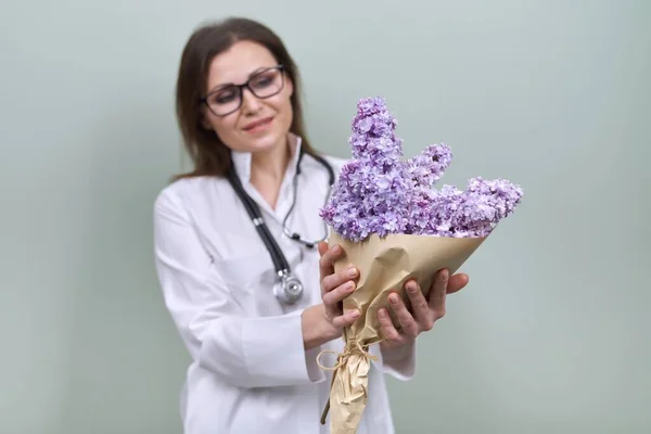 Букет з бузкових квітів в руках жінки-лікаря зі стетоскопом — стокове фото