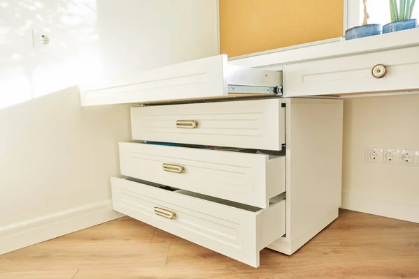 White wooden chest of drawers with vintage bronze handles under desk — Stock Photo, Image