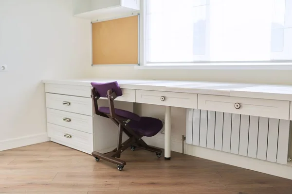 Interni, mobili bianchi, tavolo e sedia vicino alla finestra, tavola di sughero sulla parete — Foto Stock