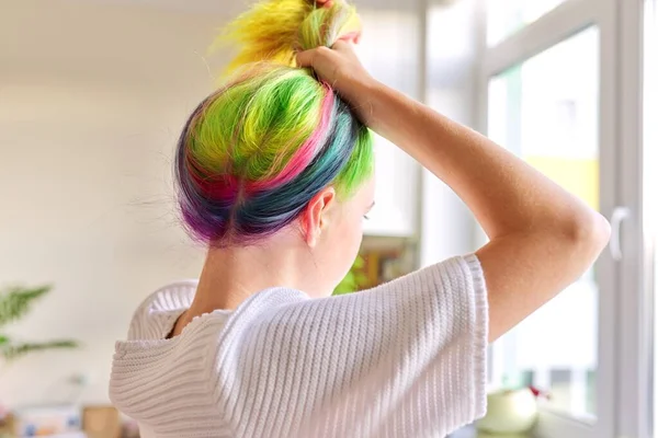 Fashionable teen girl with trendy rainbow dyed hair combing hair at home — Stock Photo, Image