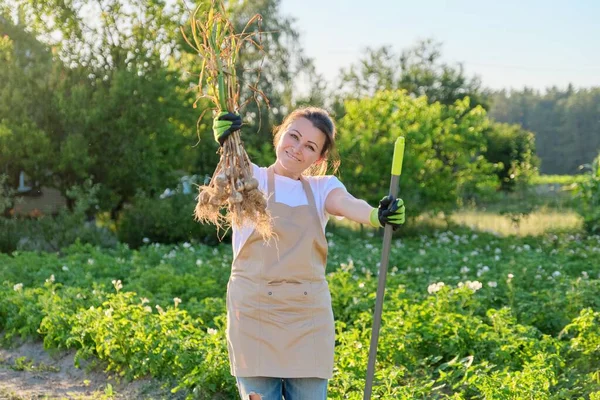 Smiling woman petani tukang kebun memegang segar digali bawang putih tanaman di tangan — Stok Foto