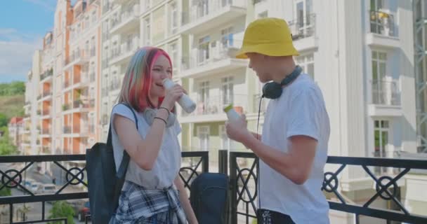 Urban lifestyle of teenagers, couple of college students talking having rest drinking milk drink in bottle outdoors — Stock Video