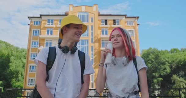 Fröhlich sprechende Studenten und Mädchen in der Stadt trinken Milchjoghurt aus der Flasche. Lebensstil, Ernährung, Jugendgesundheit — Stockvideo