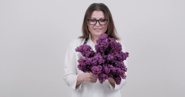 Bouquet de fleurs lilas entre les mains d'une femme médecin avec stéthoscope. — Video