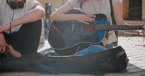 Couple of teenage hipsters street musicians making money by music, girl singing and playing acoustic guitar — Stock Video