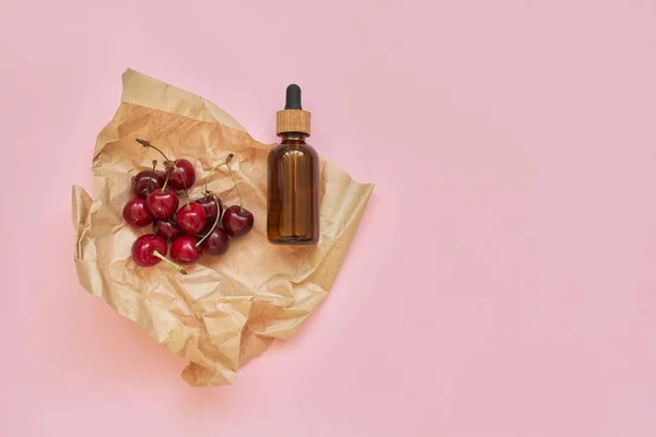 Φυσικά υγιεινά βιολογικά καλλυντικά, φρούτα, κεράσια, μπουκάλι με καλλυντικό προϊόν σε ροζ φόντο — Φωτογραφία Αρχείου