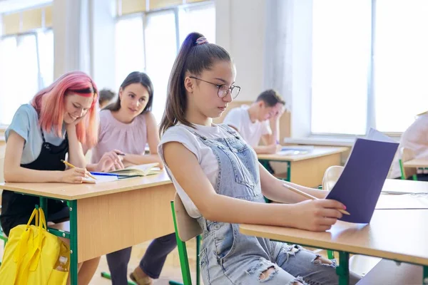 Урок в классе подростков, в передней девушки 13, 14 лет, сидя за столом — стоковое фото