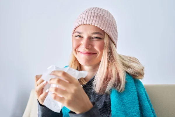 Sorrindo adolescente menina espirrando em lenço, feminino sentado em casa — Fotografia de Stock