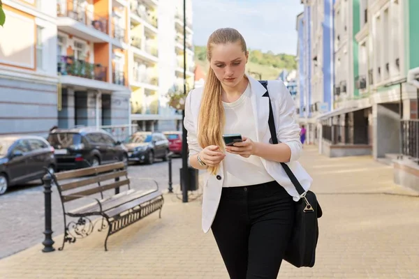 Młoda kobieta biznesu ze smartfonem spaceru ulicą miasta — Zdjęcie stockowe