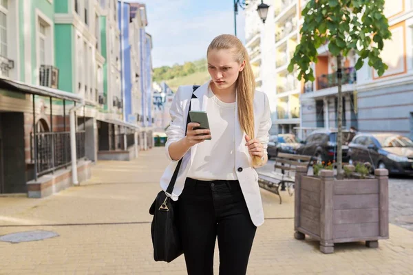 Młoda kobieta biznesu ze smartfonem spaceru ulicą miasta — Zdjęcie stockowe