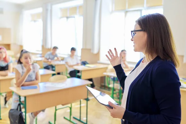 与学生在课堂上交谈的中年女教师的画像 — 图库照片