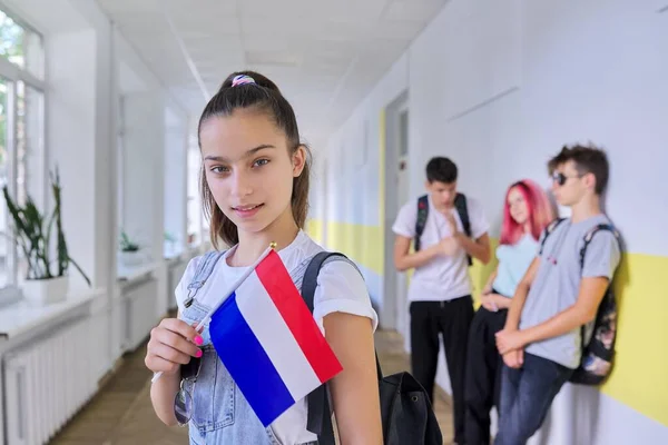 Student teenager girl with Netherlands flag inside school, school children group background — Stock fotografie