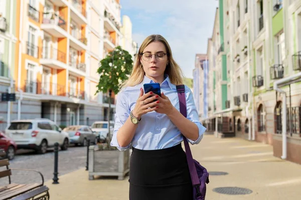 Молодая деловая женщина со смартфоном прогуливается по городской улице — стоковое фото