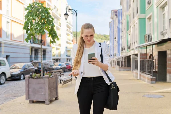 Emocje zaskoczenia na twarzy młodej kobiety biznesu patrzącej na ekran smartfona — Zdjęcie stockowe