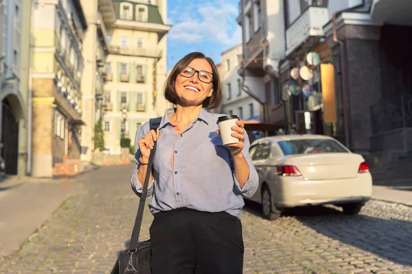 Mulher de negócios madura em óculos com saco de laptop de escritório andando ao longo da rua da cidade — Fotografia de Stock