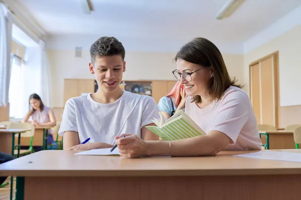 Professora de meia-idade sentada na mesa com estudante adolescente ensina — Fotografia de Stock