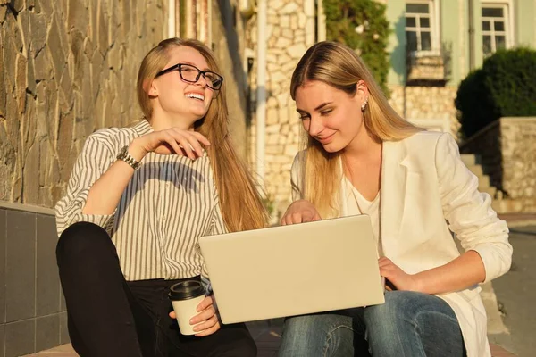 Две молодые красивые женщины веселятся, глядя в монитор ноутбука — стоковое фото