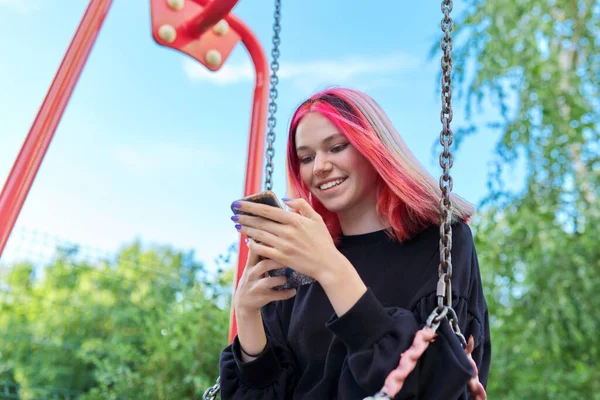 Chica adolescente feliz de moda con el pelo teñido con el oscilación del montar del teléfono inteligente — Foto de Stock