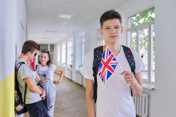 Teini-ikäinen opiskelija, jolla on Britannian lippu, koulun käytäväryhmä opiskelijoita tausta — kuvapankkivalokuva