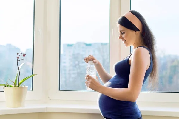Joven hermosa mujer embarazada beber agua de la botella — Foto de Stock