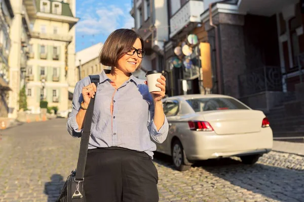 Gammal affärskvinna i glasögon med kontor laptop väska promenader längs stadens gata — Stockfoto