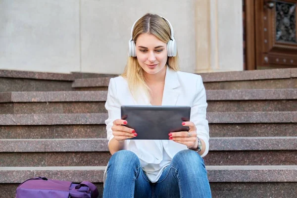 Młoda kobieta w słuchawkach z tabletem cyfrowym relaksujący siedzi na schodach w mieście — Zdjęcie stockowe