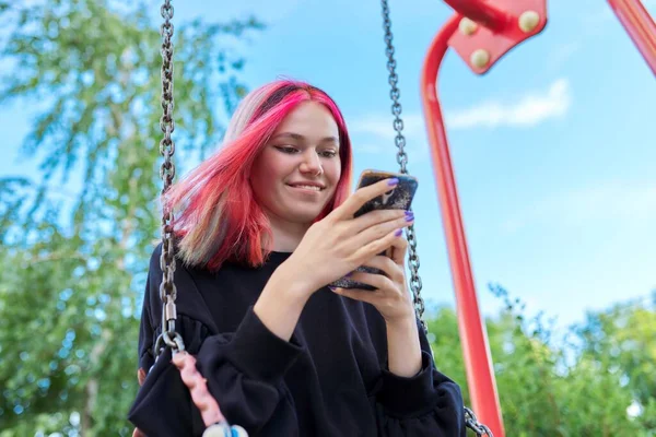 时髦的快乐少女，染发，带着智能手机荡秋千 — 图库照片