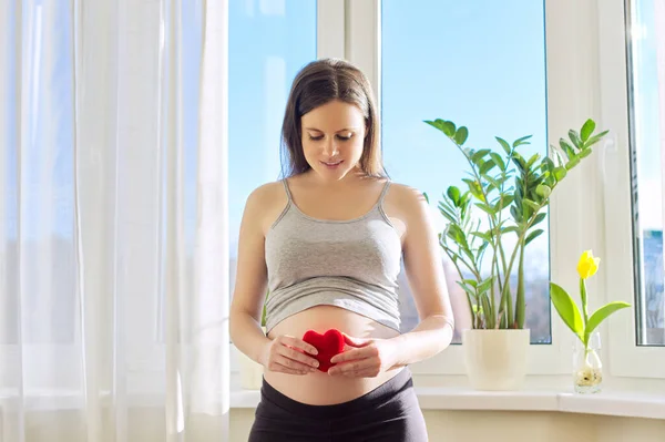 Young beautiful pregnant woman showing symbolic heart. With love for the baby — Stock Photo, Image