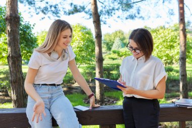 Bayan üniversite öğrencisi öğretmen, sosyal hizmetler görevlisi ve parkta oturuyor.