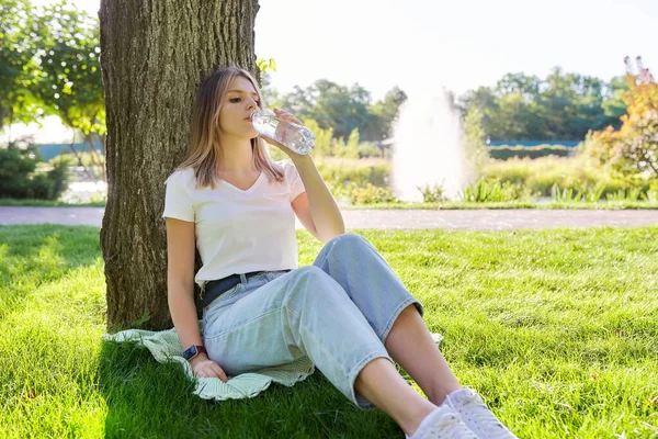 Young woman drinking water from a bottle on a hot summer day — Stock Photo, Image