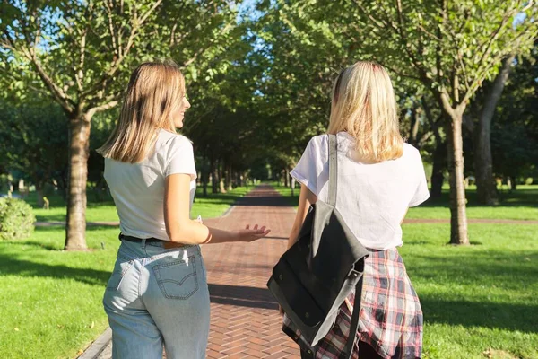 Två glada leende talande flickor tonåringar studenter promenader tillsammans, baksida visa — Stockfoto