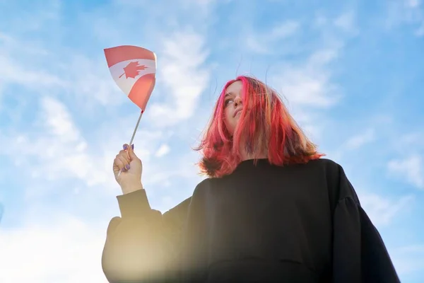 Studentka teenager s kanadskou vlajkou v ruce, modrá obloha s mraky pozadí. — Stock fotografie