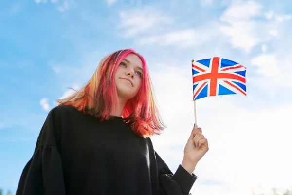 Дівчинка-підліток з британським прапором, блакитне небо з хмарами фону — стокове фото