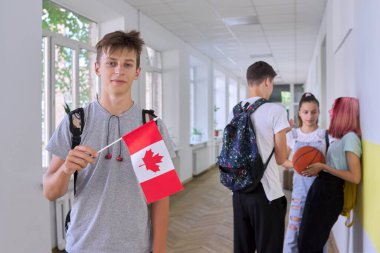 Okulun içinde Kanada bayrağı taşıyan genç bir öğrenci.