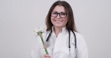 Steteskoplu kadın doktorun elinde bir buket çiçek.