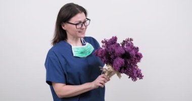 Steteskoplu kadın doktor portresi ve bir demet leylak çiçeği.