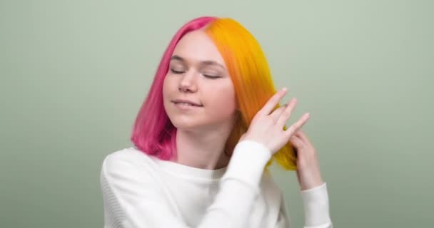 Όμορφη χαμογελαστή έφηβη κοπέλα με μοντέρνο χρωματιστό χτένισμα που δείχνει βαμμένα μαλλιά και κοιτάζοντας κάμερα — Αρχείο Βίντεο