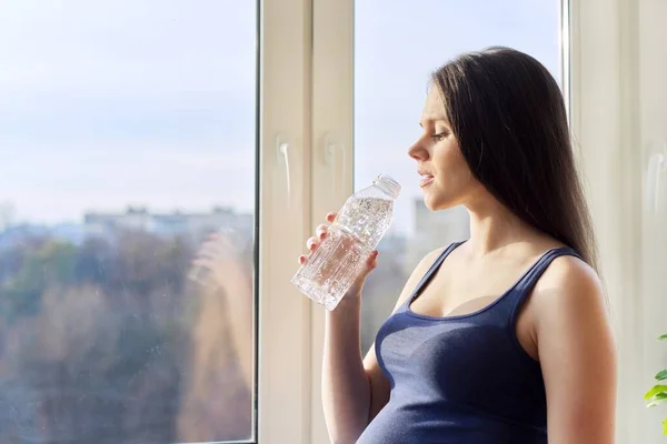 Mladý krásný těhotná žena pití vody z láhve — Stock fotografie