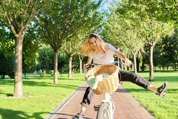 Щаслива молода жінка їде на велосипеді по дорозі в парку, красивий підліток хіпстера розважається і сміється — стокове фото