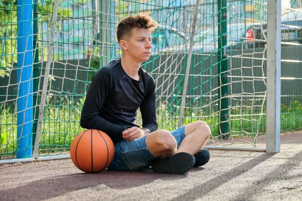 Guy teenager with ball, outdoor basketball city court background — Stock Photo, Image